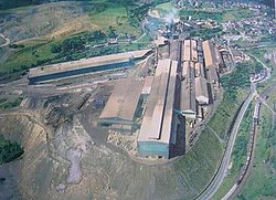 The older parts of Brymbo Steelworks in the 1970s, showing its restricted hillside site, with the melting shop (centre) and blast furnace (top) next to the village (top right). The banks shown in the foreground had covered most of the former village of Lodge. Brymbo small.JPG