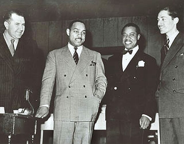 Carter stands with Robert Goffin, Louis Armstrong, and Leonard Feather in 1942.