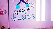 A pink wall with the words "Space Babies" written in crayon