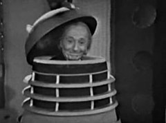 With a large grin, the Doctor emerges from the shell of a Dalek.