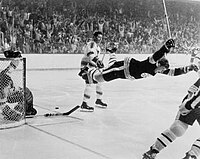 Group of hockey players. A hockey player in black is raised a few feet off the ice with his hands raised in excitement.