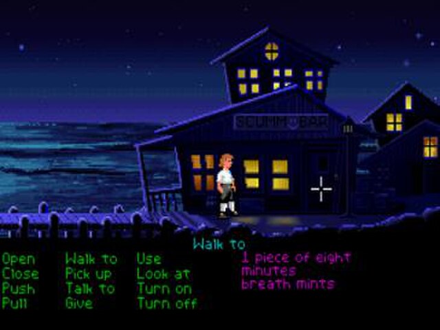 A scene in The Secret of Monkey Island shows the protagonist Guybrush Threepwood standing on the docks of Mêlée Island. Below the scene, the game disp