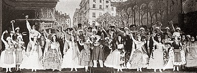 gran escenario con un gran elenco con trajes de mediados del siglo XIX en un número conjunto, con el mercado de Les Halles detrás de ellos
