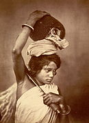 A Kochh Mandai woman of east Bengal (now Bangladesh) with an agricultural knife and a freshly harvested jackfruit. (1860)