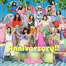 Selected members of E-girls cut and pasted in different areas in front of a colorful backdrop that features palm trees and platforms. It features the E-girls logo at the bottom, and song title situated in the middle.