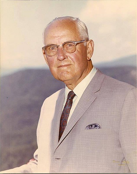 A photo of James Edgar Broyhill. He has a serious expression and glasses on. He is wearing a suit. He is older. 