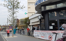 Some stores that remain open impose disciplined queuing for customers waiting to enter Social distancing outside supermarket.png