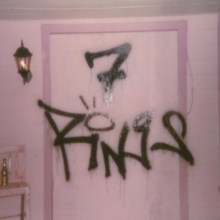 Grafiti en una pared rosa, colocado en el centro de una jamba de puerta rosa oscuro, que dice "7 RiNGS" con un punto sobre la letra que estilicé como un anillo.  En el lado izquierdo, hay una lámpara negra y una silla rosa con una botella.