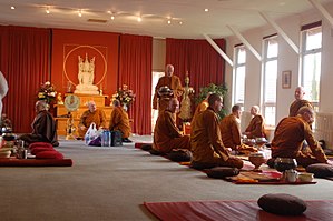 Ajahn Sumedho (seated beneath the shrine) in conversation with a bhikkhu, just before Amaravati's daily meal Luangporsumedho.JPG