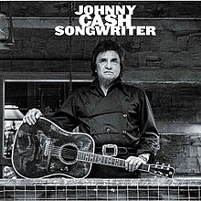 A black-and-white photograph of Cash dressed in black holding an acoustic guitar. The title and artist are written at the top of the cover.