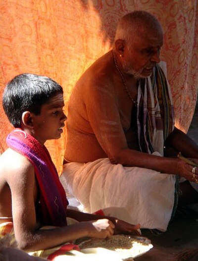Iyer priest from Tamil Nadu carrying out a small ritual with his grandson.