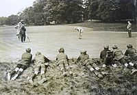Boys lying on a knoll watching golfers putting on a green below in the 1921 McVitie & Price Tournament at Oxhey Golf Club McVitie and Price Tournament - Oxhey Golf Club - 1921.JPG