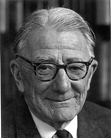 An old man, smiling slightly, in a formal suit and glasses.