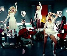 A screenshot of the music video of "Give Me All Your Luvin'" which shows Minaj (left), Madonna (center) and M.I.A. (right) as the "triple Marilyn or triple Madonna" like figures. The costume was also compared to the singer's look for her "Like a Virgin" video. Madonna-gimme-all-your-luvin.jpg