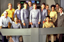 The main cast of The Motion Picture in the film's costumes on the bridge set. Clockwise from far left: director Robert Wise: Collins, Barrett, Nimoy, Doohan, Shatner, Kelley, Whitney, Nichols, Koenig, producer Gene Roddenberry, Takei, and Khambatta. These and other publicity shots were taken after screen tests for the actors on August 3, 1978.[6]: 28 