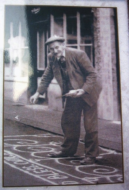 A resident of the town sanding the street in celebration of May Day 1920. The custom continues to this day.