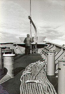 An able seaman stands iceberg lookout on the bow of the freighter USNS Southern Cross during a re-supply mission to McMurdo Station, Antarctica; c. 1981. Crewmember doing iceberg lookout on the USNS Southern Cross (Ross Sea, Antarctica, 1981).jpg