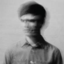 A blurred black and white picture of a man moving his head from left to right.