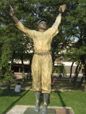 A statue of a baseball player with his arms in the air.