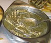 Eel meat in a green herb sauce in a metal serving dish