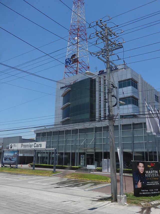 Corporate Guarantee and Insurance Company building, the headquarters of CLTV 36, a four-story modern office building with a tall red and white antenna behind a BMW dealership, on Jose Abad Santos Avenue in San Fernando, Pampanga, April 2017