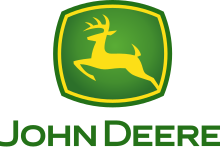 A green, rounded square with a yellow jagged outlines on the four sides of the square near the outside of its green border can be seen. In the middle of the yellow outline, a biological entity drawn outlined in yellow can be seen in a leaping position. This animal is commonly referred to as a deer. Underneath the deer and the green box, the words in caps lock, 'JOHN DEERE' can be read.