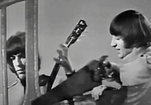 Ringo Starr (right) sawing though the studio scenery in one of the promo clips for the song