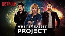 The three presenters standing together. Netflix logo is prominently shown on the top left. At the bottom in stylized white writing is the show title. A rabbit symbol appears between the words white and rabbit.