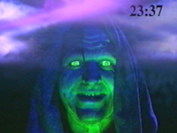 An image of the video videotape with the Gatekeeper on screen talking to players with the game clock in the right-hand corner and the CGI storm in the background. The Gatekeeper in The Harbingers.png