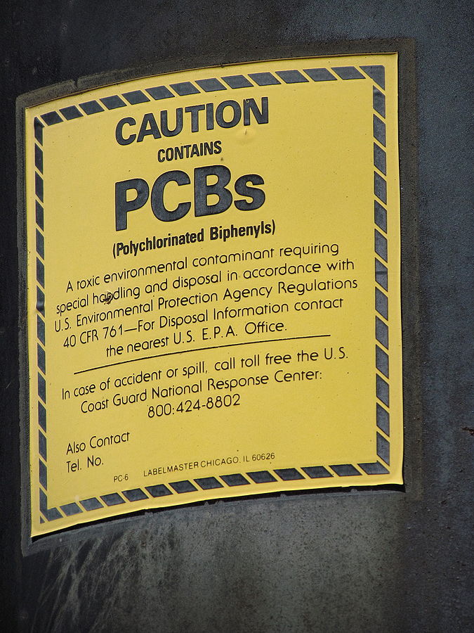 PCB warning label affixed to a railroad signal power supply transformer dating from the 1930s