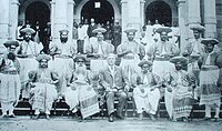 A group of British appointed Kandyan chiefs, with Hon. J. P. Lewis, Government Agent in 1905. The chiefs have adopted the dress of traditional Dissawas by this time but still haven't started using other traditional insignia of high offices such as jewellery, ceremonial daggers or footwear. Kandyan Chiefs in 1905.JPG