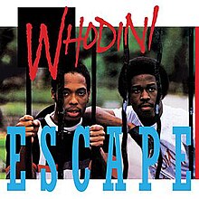 Two members of Whodini looking through a wrought-iron fence