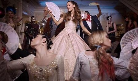 Grande wearing a pink dress in a masqueraded, costume Victorian-era inspired party while surrounded by party guests during the music video (as illustr