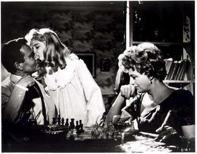 Lolita kisses Humbert goodnight as he plays chess with her mother. His line in the scene is "I take your Queen." Chess, a recurring motif in Nabokov's