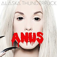 Gambar seorang pria di tarik, dengan lensa kontak dan kuku yang panjang, dengan kata "ANUS" dicetak di gambar