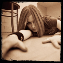Avril Lavigne ditampilkan tergeletak di tanah dan melihat ke kamera. Tidak ada kata-kata dalam pic.