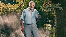 David Attenborough standing in front of a tree