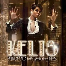 Kelis leaning against a large window with a cityscape shown in the reflection. The title of the song and Kelis' name are superimposed over the image.