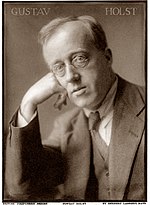 A sepia-toned white man in glasses and a suit looks at the viewer.