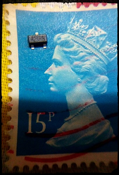 A MOSFET transistor, placed upon a British postage stamp for size comparison.