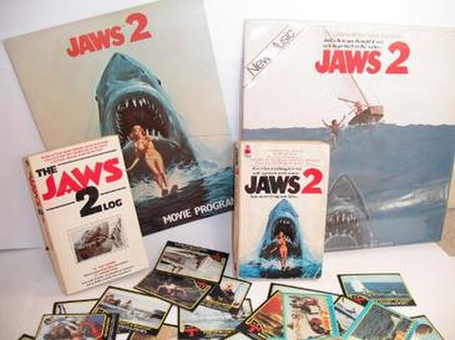 A selection of merchandise from Jaws 2. Top: Movie Program; Soundtrack LP Album, Middle: The Jaws 2 Log by Ray Loynd; Jaws 2 novelization by Hank Sear