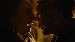 An infected human moves in to kiss a shocked woman, with tendrils connecting their mouths.