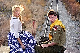 Roy Parker (Ryan Kelley) and friend Ellie (Arielle Kebbel) perch precariously atop a moving train, one of the film's chase scenes, as backlighting by cinematographer T. C. Christensen imparts a halo effect Outlaw Trail film scene.jpg