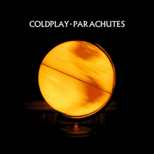 A close-up photograph of a yellow globe in a darkened room. The globe is spinning and illuminated from the inside. The words "COLDPLAY • PARACHUTES" are written in white text above the globe.