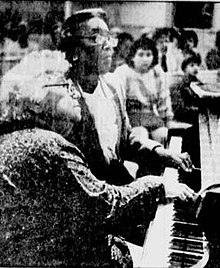 Ruth Eisenberg and Margaret Patrick playing piano, using one hand each. Eisenberg-Patrick.jpg