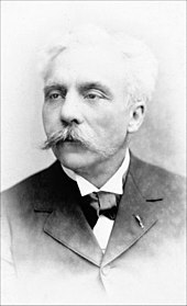 middle-aged man with full head of white hair and large white moustache