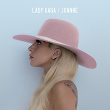 Left profile picture of Lady Gaga wearing a wide pink hat, in front of a sky-blue background.