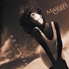 A brunette woman in a white low-cut minidress standing in front of a dark, sepia-toned desert-like background, hair flailing upward in the wind, the words "MARIAH CAREY" on the upper right hand side of the artwork and the word "EMOTIONS" vertically spelled out from the top down towards the bottom left hand side of the artwork.