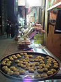 یکی از نان برنجی پزها در بازار کرمانشاه که برای امتحان کردن طعم شیرینی‌هایش آن‌ها را بر روی سینی قرار داده.