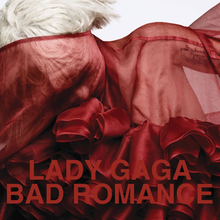 Upper bust of a woman with short cropped hair. Her body and her face is covered by a red translucent cloth with intricate wrappings in the front. Over the image the words "Lady Gaga" and "Bad Romance" are written in red capital letters. The photograph was shot by Heidi Slimane.